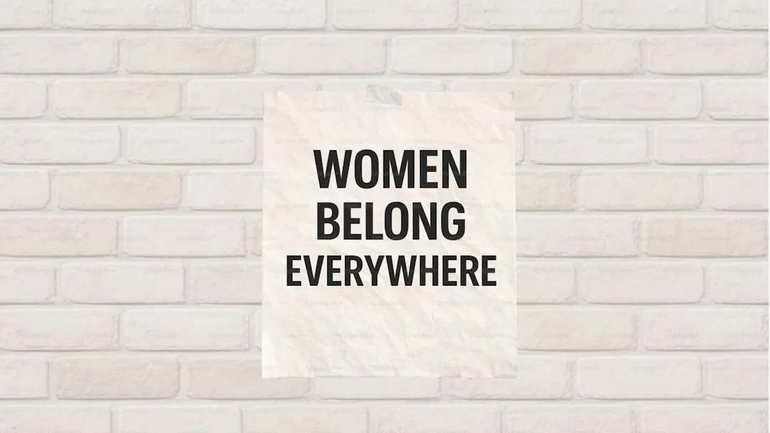 Affiche avec le texte « les femmes appartiennent partout » sur un mur de briques